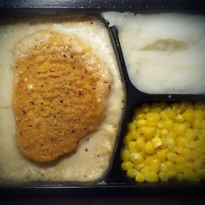 An image of a heavily processed meal of fried chicken, mashed potatoes, and corn