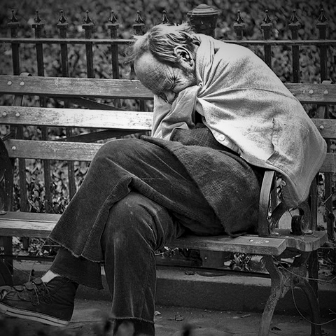 Man sitting on park bench trying to get warm