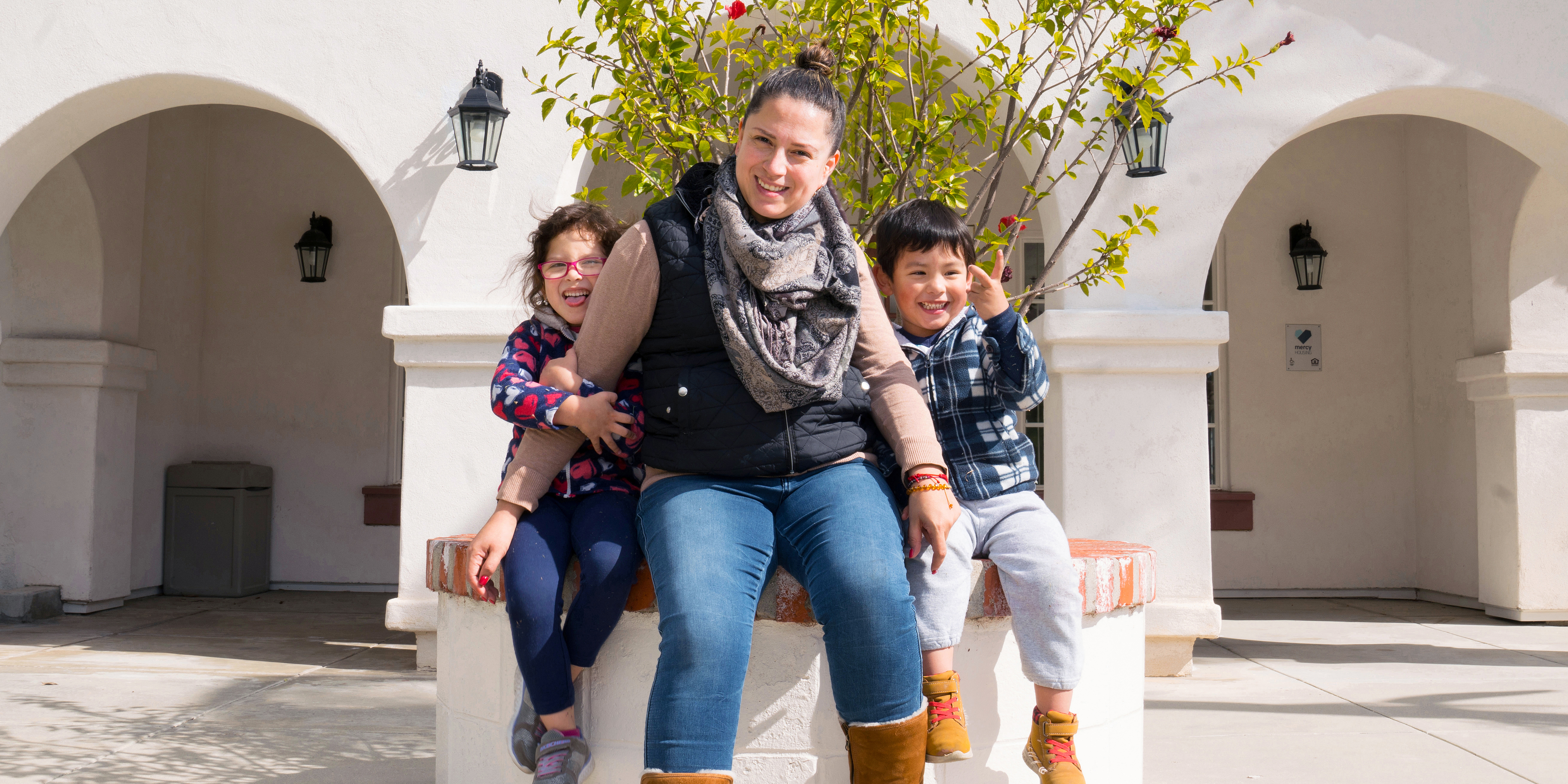 Angela with her two children sit outside of Casa San Juan