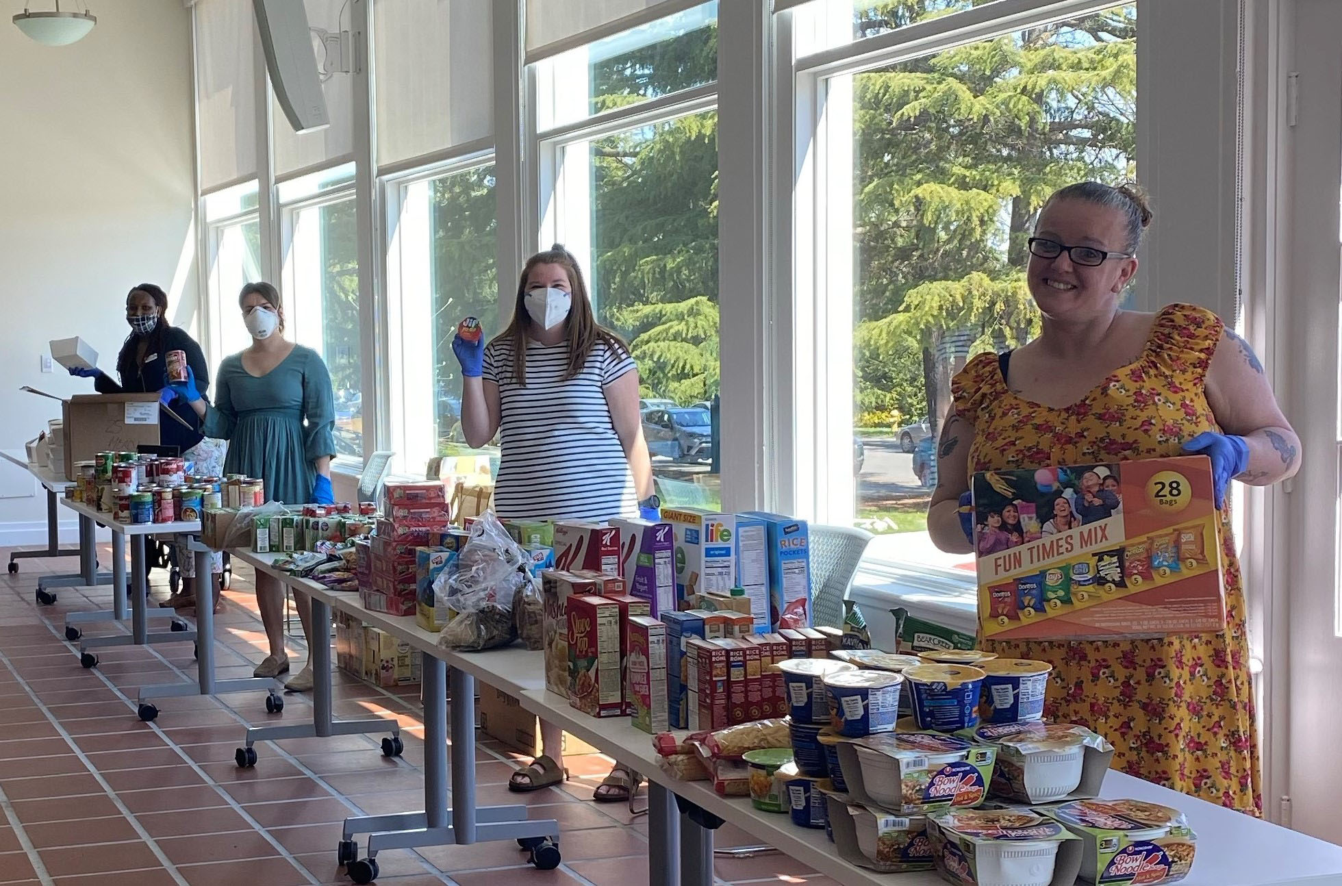 Resident Service staff smilling in masks behind food tables