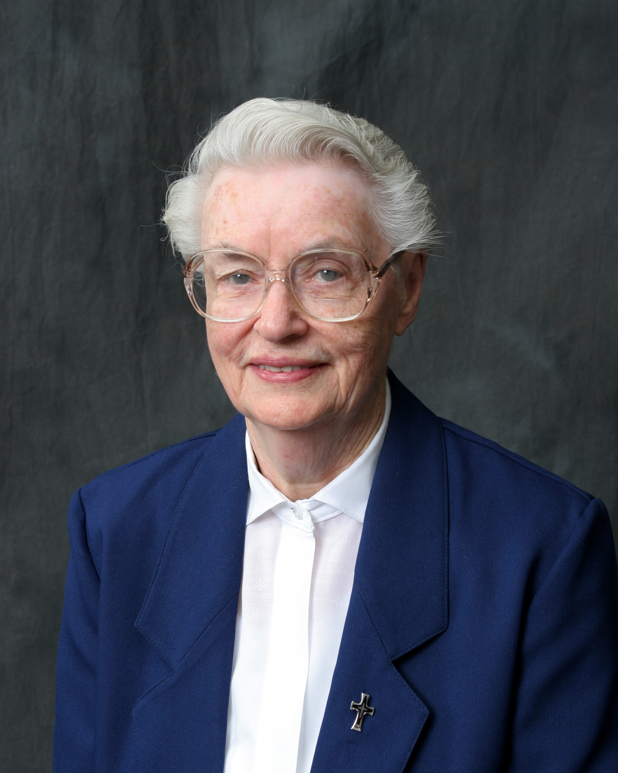 Headshot of Sister Mary Terese Tracy, smiling against a grey background