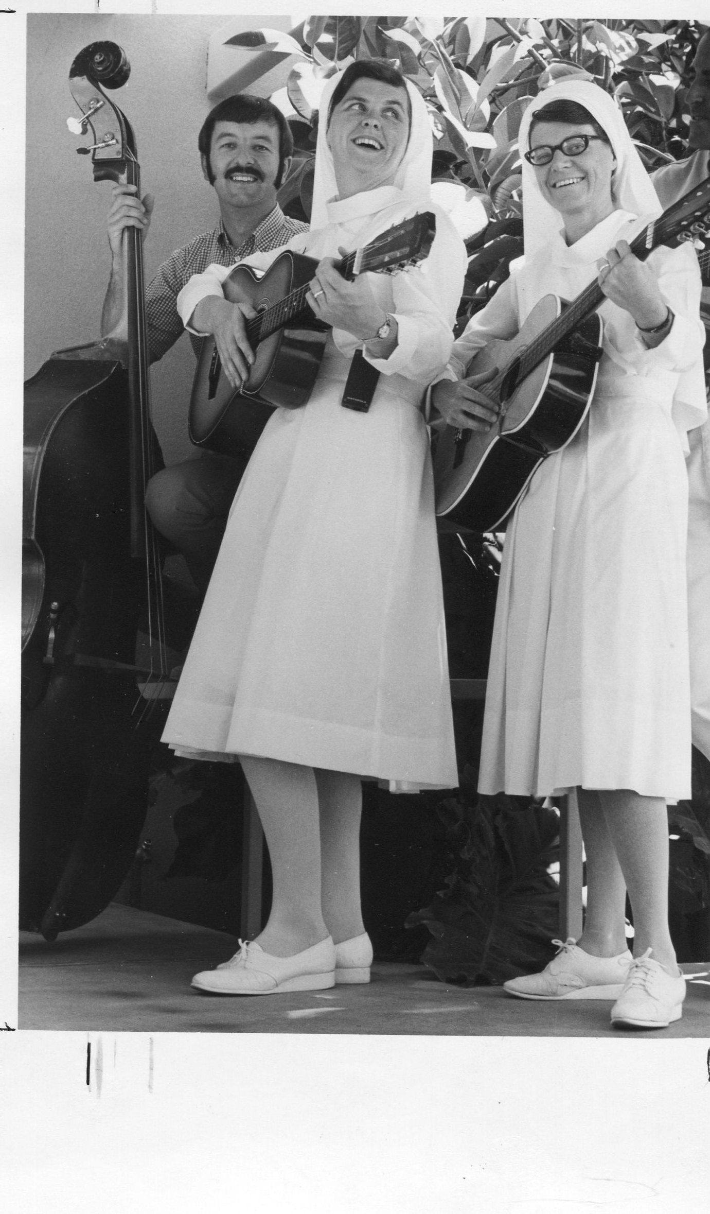 Sister Lillian playing guitar alongside other sisters and a man playing a cello.