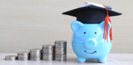 Piggy bank with grad hat and stacks of coins